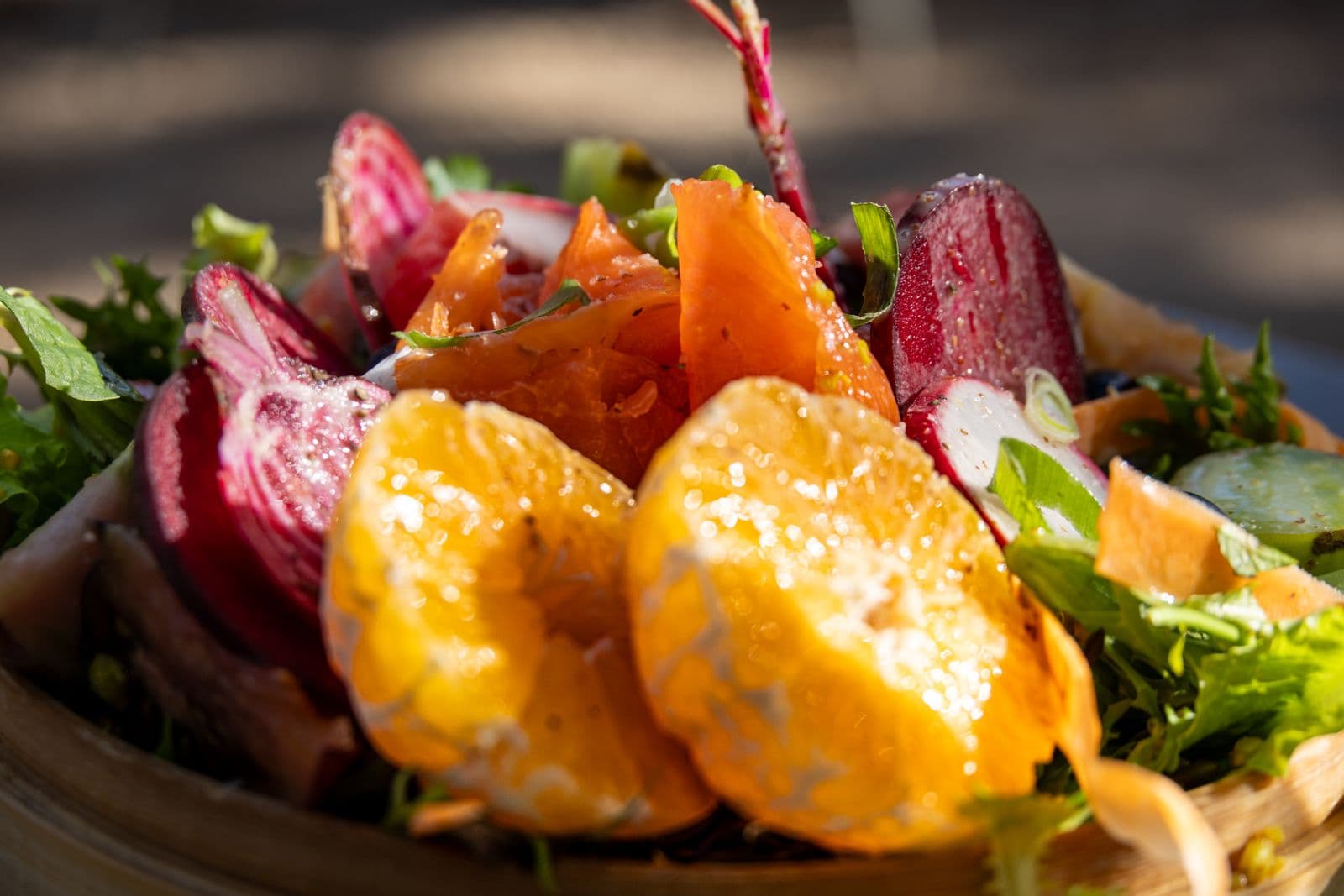 A salad of beetroot, orange segments and greens in a wooden bowl